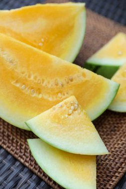 Hasır masada olgun sarı karpuz parçaları, yakın plan.