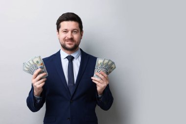 Gri arka planda dolar banknotları olan açgözlü bir bankacı. Metin için boşluk