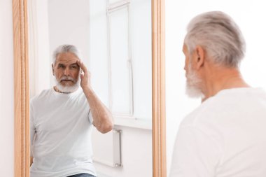 Yakışıklı son sınıf öğrencisi aynada kendine bakıyor.