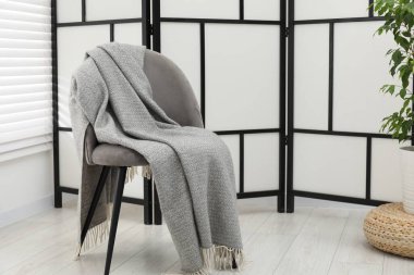 Gri yün battaniyeli rahat bir koltuk.