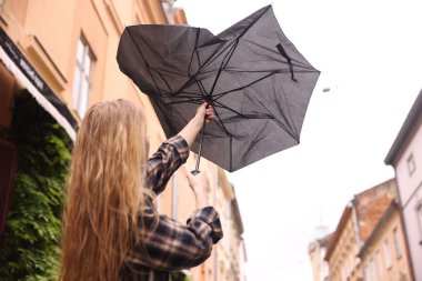 Açık havada şemsiyesi kırık bir kadın, düşük açılı.