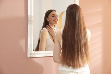 Güzel bir kadın aynada kendine bakıyor.