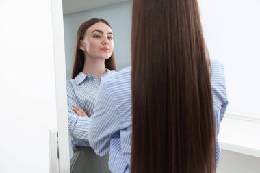 Güzel bir kadın aynada kendine bakıyor.