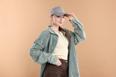 Bej arka planda şık bir beyzbol şapkası takmış güzel bir kadının portresi.