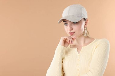 Bej arka planda şık bir beyzbol şapkası olan güzel bir kadın. Metin için boşluk
