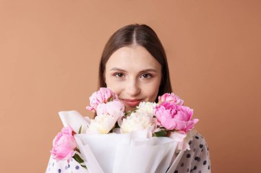 Koyu bej arka planda şakayık demeti olan güzel bir kadın.