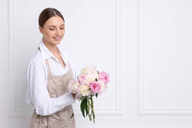 Beyaz duvarın yanında güzel şakayık demeti olan bir çiçekçi.