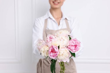 Beyaz duvarın yanında güzel şakayık demeti olan bir çiçekçi, yakın plan.