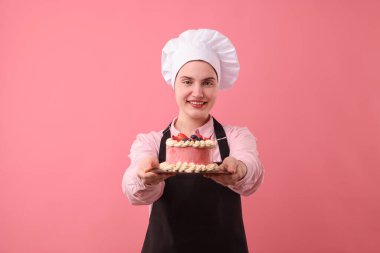 Şekerci pembe arka planda lezzetli bir pasta tutuyor.