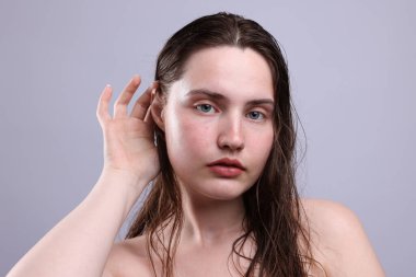 Gri arka planda doğal ten rengi olan kadın portresi, yakın plan.