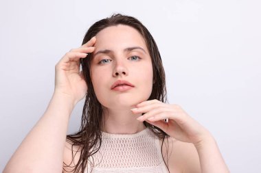 Açık gri arka planda doğal ten rengi olan güzel bir kadının portresi. Yakın plan.