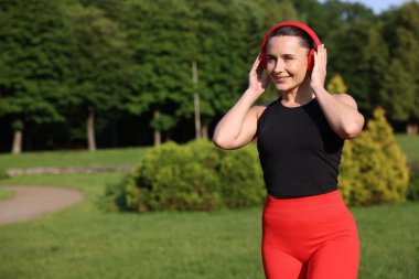 Kulaklıklı mutlu kadın dışarıda, mesaj için yer var. Sağlıklı yaşam tarzı