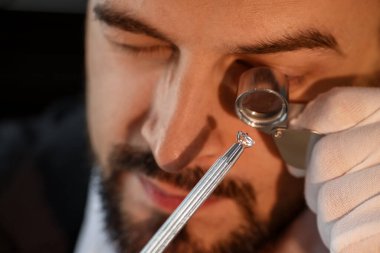 Kapalı alanda lüks mücevher değerlendirmesi yapan loupe 'a değer biçen bir eksper.