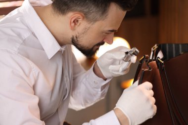 Kapalı alanda deri çanta değerlendirmesi yapan bir eksper.