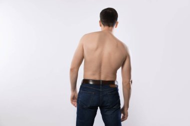 Kotlu bir adam açık gri arka planda poz veriyor.