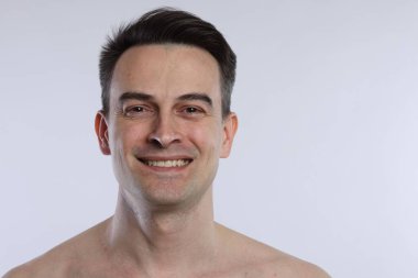 Açık gri arka planda gülümseyen adamın portresi, yakın plan.