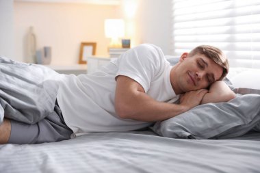 Evdeki yumuşak yatakla yatakta uyuyan genç adam.