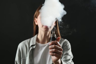 Siyah arkaplanda elektronik sigara içen kadın