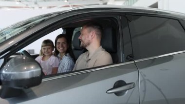 Mutlu aile yeni arabanın içinde konuşuyor, kamera yakınlaşıyor.