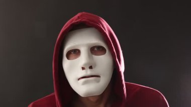 Anonimlik. Gri arka planda sessiz jest yapan maskeli adam.