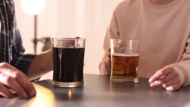 Gri masada bira bardaklarını tokuşturan arkadaşlar, yakın plan.