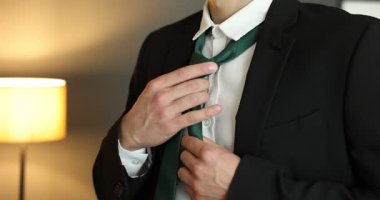 Evde şık kravat bağlayan adam, yakın plan.