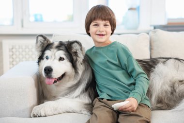 Mutlu çocuk ve sevimli köpek evdeki kanepede.