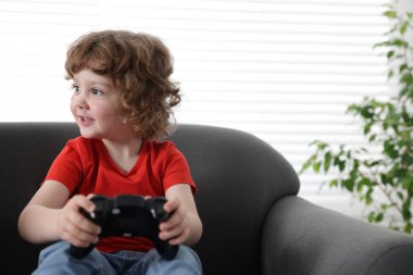 Küçük çocuk evdeki kanepede oyun kumandası oynuyor, mesaj için yer var.