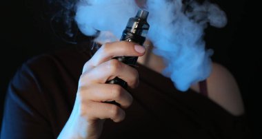 Siyah arka planda neon lambalarda elektronik sigara içen kadın, yakın plan