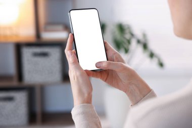 Evde modern akıllı telefon kullanan bir kadın, yakın çekim. Metin için boşluk