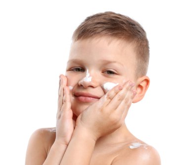 Küçük çocuk beyaz arka planda cildine güneş kremi sürüyor.