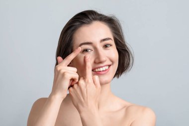 Kadın ışık arkaplanına kontak lens takıyor