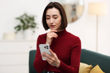 Evde modern akıllı telefon kullanan güzel bir kadın.