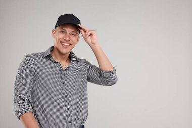 Açık gri arka planda şık siyah beysbol şapkası giyen genç adam, mesaj için yer var.