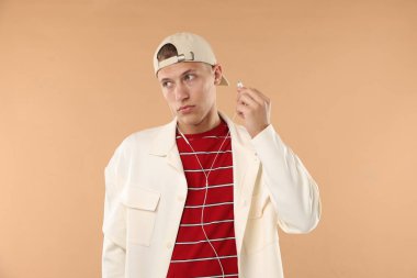 Beyzbol şapkalı, kulaklıklı genç bir adam.