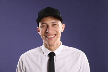 Koyu mavi arka planda şık beysbol şapkalı genç adam.