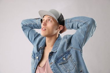 Açık gri arka planda şık bir beyzbol şapkası takan genç adam.