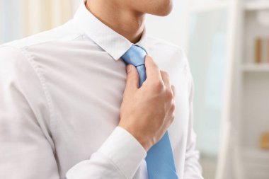 Evde şık kravat bağlayan adam, yakın plan.