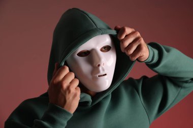 Anonimlik. Kırmızı arka planda maske takan adam