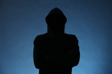 Mavi arka planda kapüşonlu isimsiz bir adamın silueti.