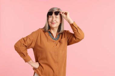 Pembe arka planda şık giyinmiş son sınıf öğrencisi bir kadın.