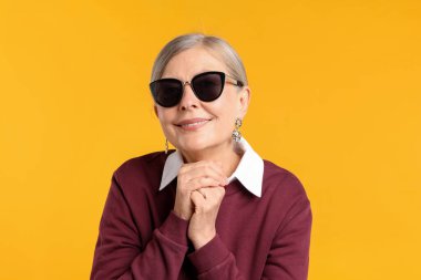 Turuncu arka planda şık giyinmiş mutlu bir son sınıf kadını.