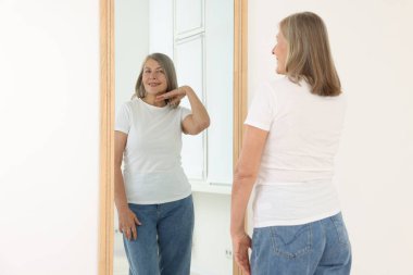 Güzel son sınıf öğrencisi kadın aynada kendine bakıyor.