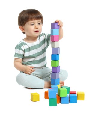 Beyaz arka planda renkli küplerle oynayan sevimli küçük çocuk.