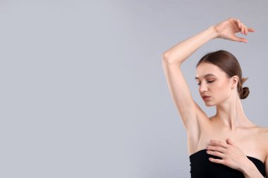 Gri arkaplandaki epilasyondan sonra pürüzsüz cilt gösteren genç kadın, metin için boşluk