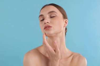 Açık mavi arka planda büyüleyici genç bir kadının portresi.