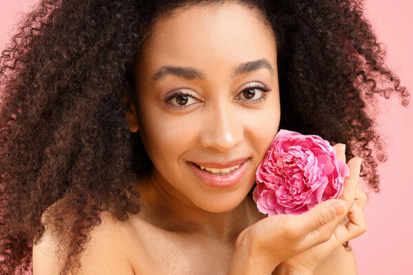 Beautiful Brazilian woman with peony flower on pink background, closeup