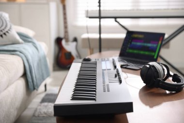 MIDI klavye, dizüstü bilgisayar ve kulaklıklar ev stüdyodaki ahşap masada, seçici odaklanma