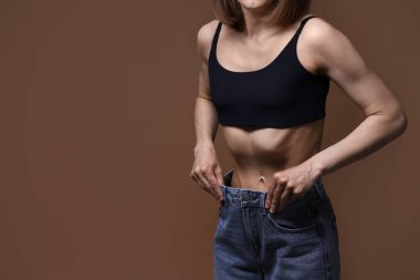 Kahverengi arka planda anoreksiden muzdarip bir kadın, yakın plan. Metin için boşluk