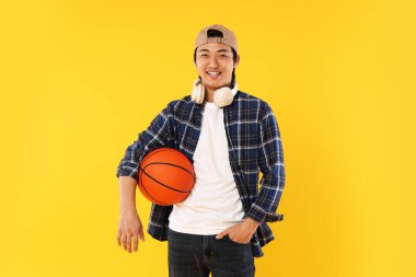 Kulaklıklı ve turuncu arka planda basketbol topu olan bir öğrenci.